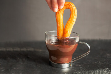 Dipping traditional Spanish sweet called Churros in hot chocolate