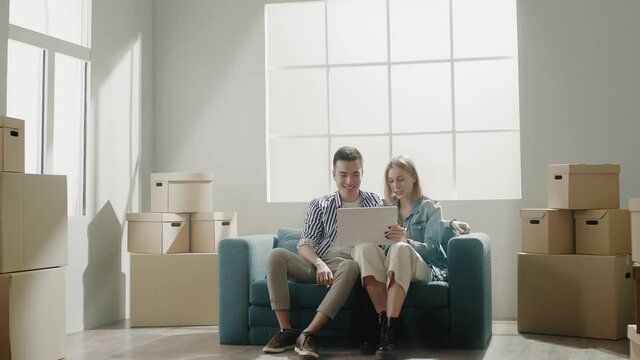 Couple of woman and man sits on sofa and relax after moving