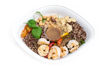 Healthy and delicious take-away shrimp salad in white plastic container. Salad with king prawns, warm grilled vegetables, quinoa, chickpeas, tomatoes and hummus. Take-out food. Balanced lunch.
