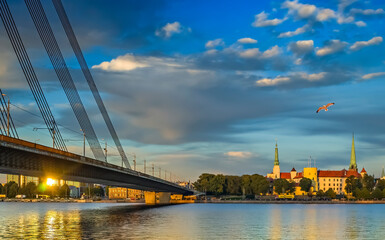 Obraz premium View on cable bridge and historical district of Riga - the capital of Latvia and famous Baltic city widely known among tourists due to its unique medieval and Gothic architecture