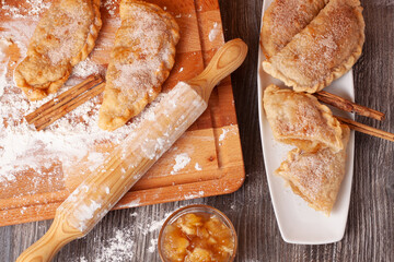 Vista cenital de un plato de empanadillas rellenas de crema de manzana con una tabla de madera,un...