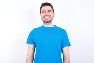 young handsome caucasian man wearing blue t-shirt against white background with a happy and cool smile on face. Lucky person.
