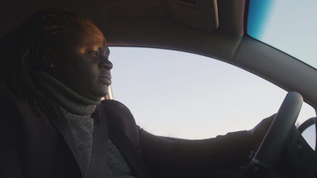 Young african american black man using smartphone while driving. High quality 4k footage