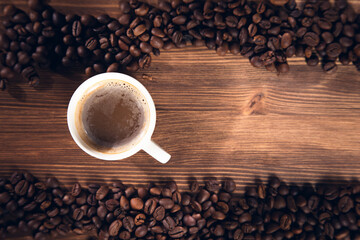 cup of coffee with coffee beans on wooden background