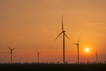 silhouettes of wind generators with sun in golden lights with copy space