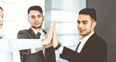 Fototapeta premium Business people group showing teamwork, joining hands and giving five to each other in modern office. Success concept