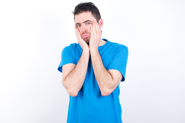 young handsome caucasian man wearing blue t-shirt against white background Tired hands covering face, depression and sadness, upset and irritated for problem