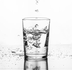 Water being poured into a glass. White background..