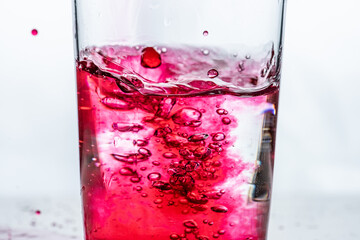 Red liquid being poured into a glass. White background..