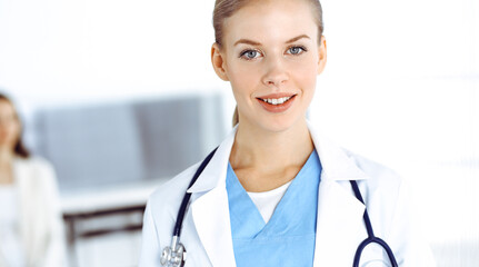 Woman - doctor standing in clinic. Physician at work, studio portrait. Medicine and health care concept