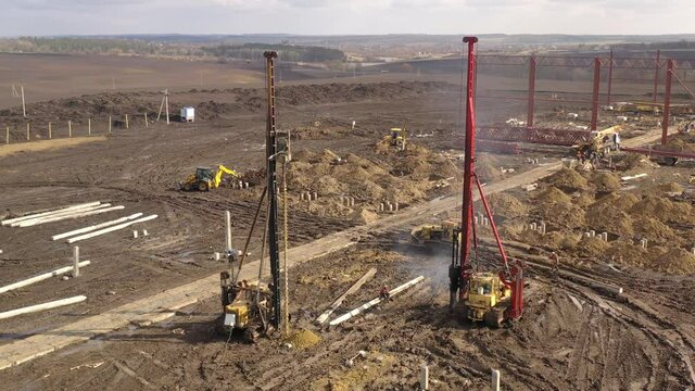 Excavation at a construction site, diesel pile driving machine with rumble and smoke drives piles deep into the ground to ensure the strength of the foundation of the future structure