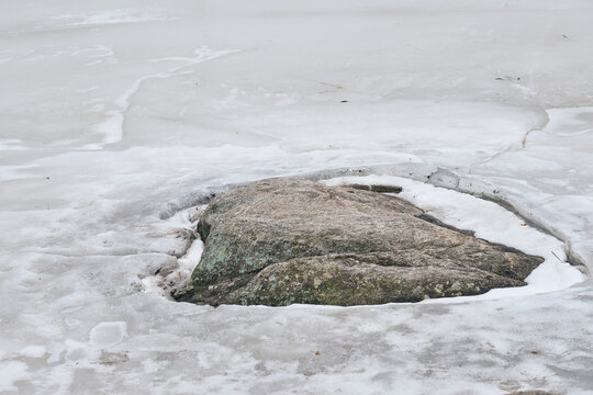 Ice around the stone on the river in early spring.