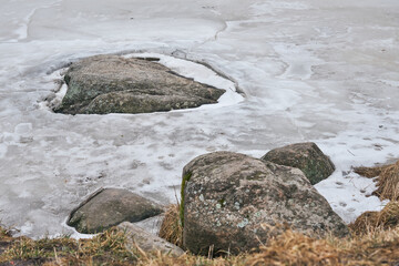 Ice around the stone on the river in early spring.