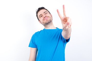 young handsome caucasian man wearing white t-shirt against white background directs fingers at camera selects someone. I recommend you. Best choice