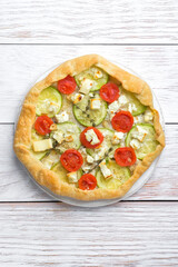 Rustic homemade galette with cheese and vegetables on a rustic background top view with copy space.