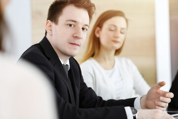 Businessman headshot at meeting in sunny office. Unknown entrepreneur sitting with colleagues at the background