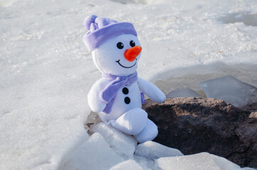 toy snowman on an ice floe in the snow
