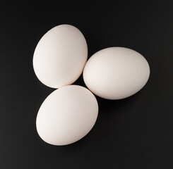 Chicken eggs with white shells on black background isolated