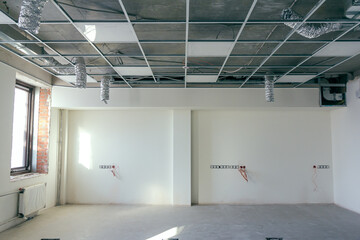 The hanging ceiling in the office under construction. The ceiling false system. Suspended ceiling frame and board under construction at the construction site.