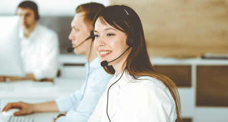 Group of diverse operators at work in call center. Beautiful asian woman sitting in headset at customer service office. Business concept