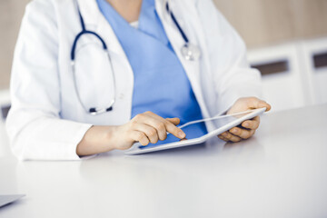 Unknown woman-doctor standing in clinic and using tablet pc, close-up. Data and best service in medicine and healthcare