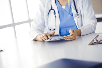 Unknown woman-doctor standing in clinic and using tablet pc, close-up. Data and best service in medicine and healthcare