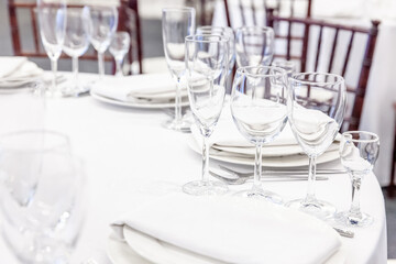 Fancy table set for dinner with napkin glasses in restaurant, luxury interior background. Wedding elegant banquet decoration and items for food arranged by catering service on white tablecloth table.