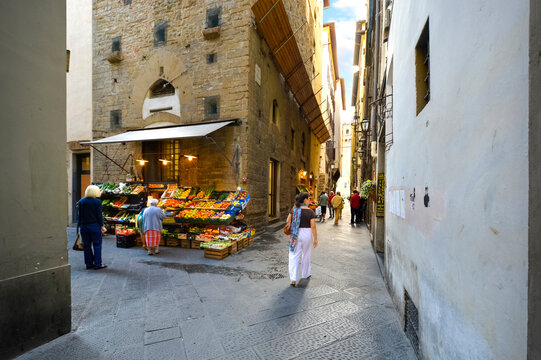 Italians enjoying a narrow back alley with a fresh produce market near Piazza di Signoria in the Tuscan city of Florence, Italy.