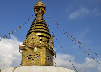 Close-up of Buddha's eyes in Swayambhunath stupa. There are prayer flags hanging on it. Kathmandu, Nepal.