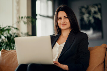 A confident financial manager. The lawyer is a business woman with a brunette European appearance. Works on a laptop computer. Located in a modern, stylish coworking office.