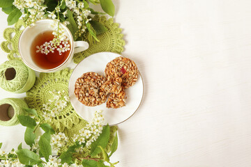 A cup of tea with cherry branches, yarn and handmade motifs, cookies on a white background, top view, space for text
