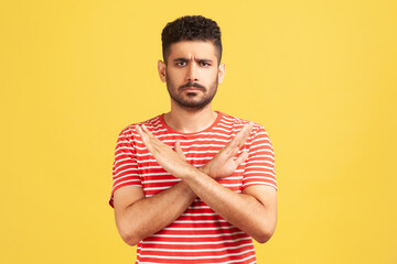 There is no way. Concerned bearded man in striped t-shirt crossing hands showing x gesture,...