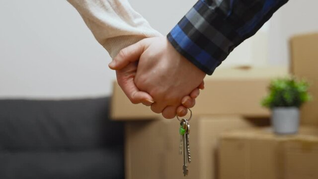 Family couple holding key to new home on moving day.