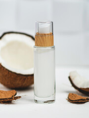 Glass bottle with coconut oil and half a coconut on a white background. Cosmetic coke oil. Health and beauty concept.