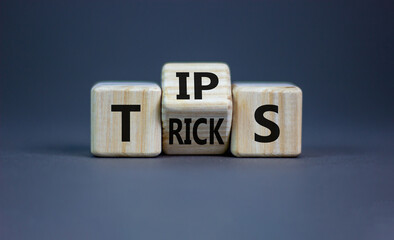 Tips and tricks symbol. Turned the wooden cube and changed the word 'tips' on 'tricks'. Beautiful grey background. Business and tips and tricks concept, copy space.
