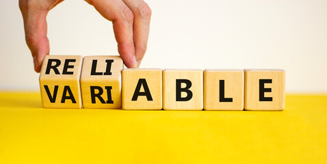 Variable or reliable symbol. Businessman turns wooden cubes and changes the word variable to...