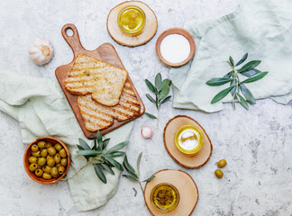 Fototapeta na wymiar Green olives, olive oil and ciabatta bread. Top view flat lay with copy space