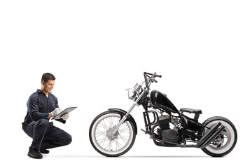 Fototapeta na wymiar Motorbike mechanic kneeling and checking a chopper
