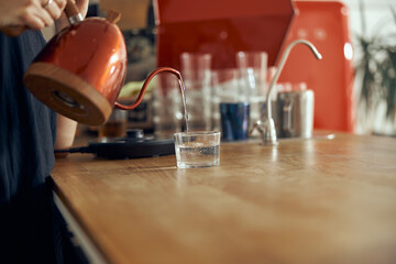Professional barista pours water, hands close-up. Pouring water in glass