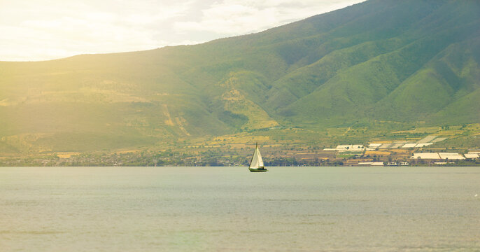 Boat in the water, scenery of mountains and sea. Feeling of grandeur, solitude.