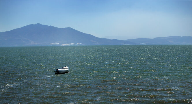 Boat in the water, scenery of mountains and sea. Feeling of grandeur, solitude.