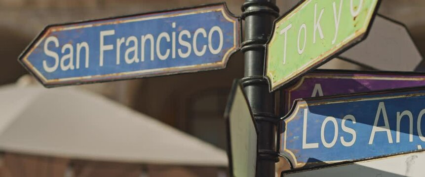 Touristic signpost showing directions to the different cities in the world: San Francisco, Tokyo, LA, Madrid. Slow motion, close up.