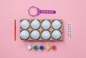 Eggs in a tray and paint on pink.