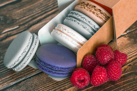 Colored macaroon and raspberry cookies in a paper box