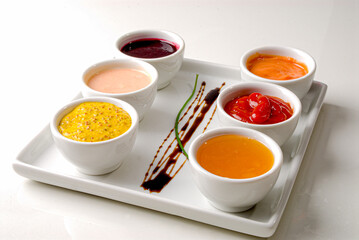 Jars of mustard sauces, ketchup, mayonnaise, honey, hot sauce on a white background