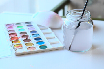 Selective focus shot of watercolor paints and a brush in a jar full of water