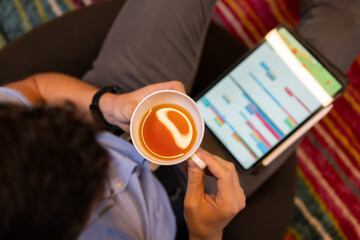 Man drinking tea near tablet