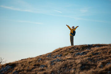 Successful woman raising hands on mountain