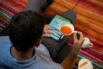 Man drinking tea near tablet