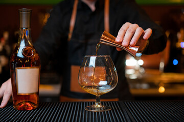 Waiter pouring cognac into the cup